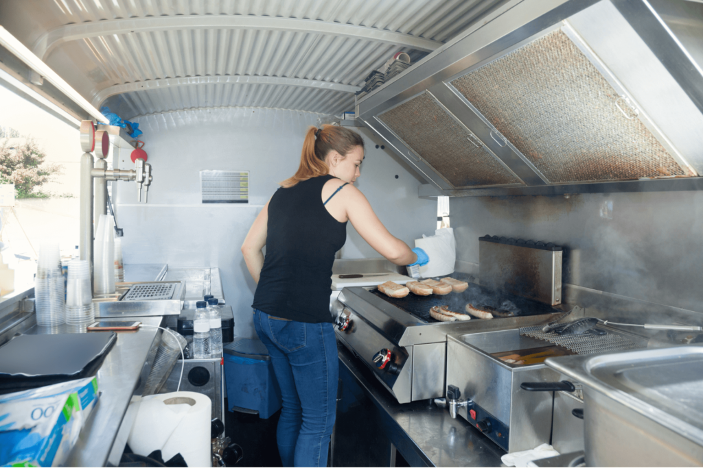 Une propriétaire de foodtruck en plein usage de sa hotte répondant aux normes réglementaires